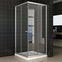 Cabine de douche carrée avec portes vitrées, profilés argentés et receveur de douche blanc, dans une salle de bain avec carrelage mural noir et un miroir.