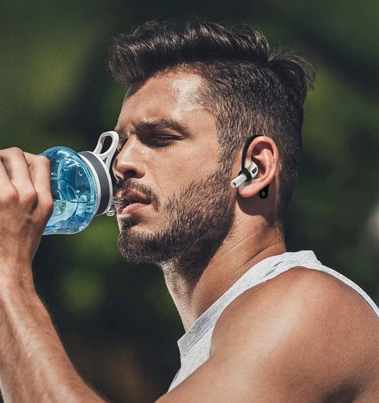 Homme portant des crochets d'oreille de sport, buvant de l'eau.