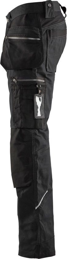 Pantalon de travail noir, vue de côté, avec de nombreuses poches, fermetures éclair et détails réfléchissants.