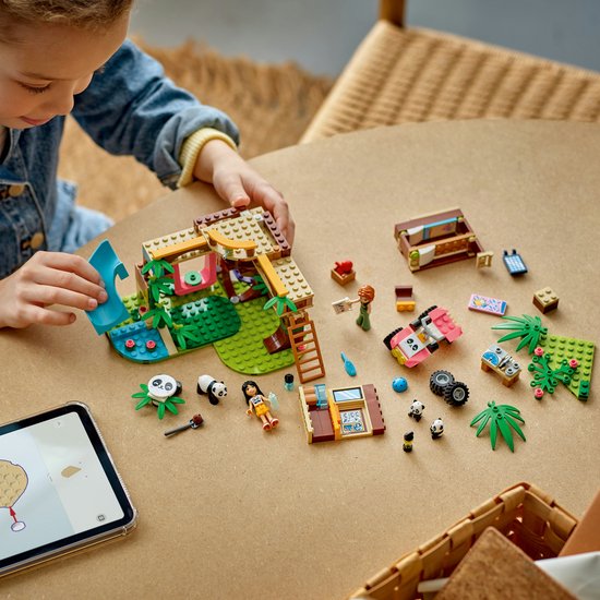Meisje speelt met de LEGO Friends Pandaopvang set, quad en losse onderdelen op tafel.