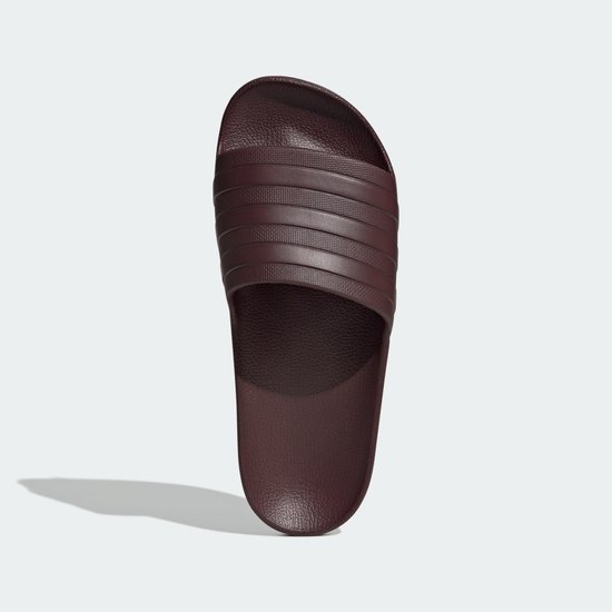 Tongs Adidas Adilette bordeaux foncé avec trois bandes sur la bride et logo sur la semelle.