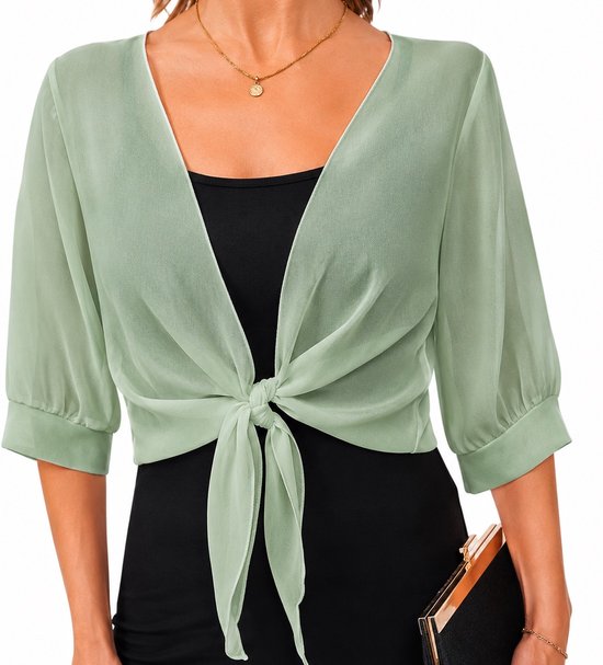 Model draagt een lichtgroen chiffon vestje met V-hals, gedrapeerd over een zwarte jurk en geknoopt aan de voorkant.