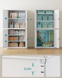Witte metalen kast met open deuren, gevuld met mappen, boeken, sportartikelen en dozen. Toont de 2 cm diepe planken en het mechanisme van de deuren.