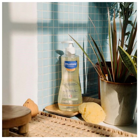 Mustela reinigingsolie naast een spons en planten.