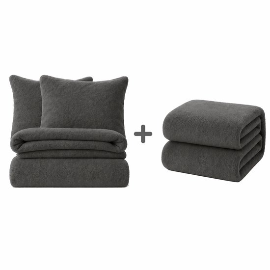 Set van antracietkleurige kussenslopen en een dekbedovertrek naast een gevouwen plaid.