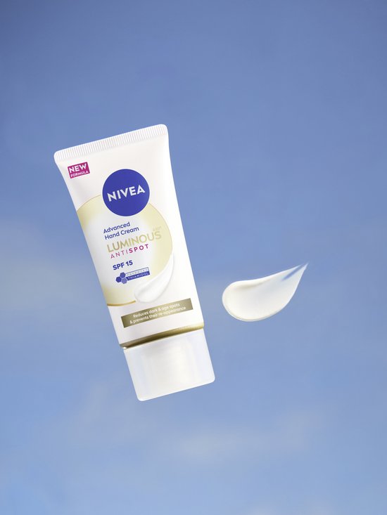 NIVEA Luminous 630 Anti-Spot geavanceerde handcrème met SPF 15 zweeft met een druppel crème tegen een blauwe hemel.