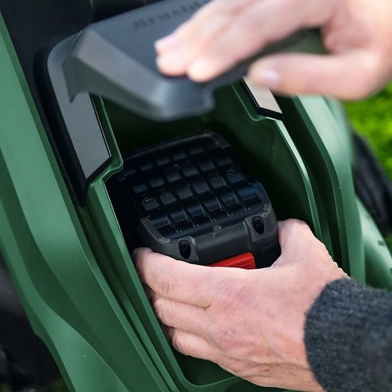 Groene Bosch grasmaaier, een hand plaatst de accu.
