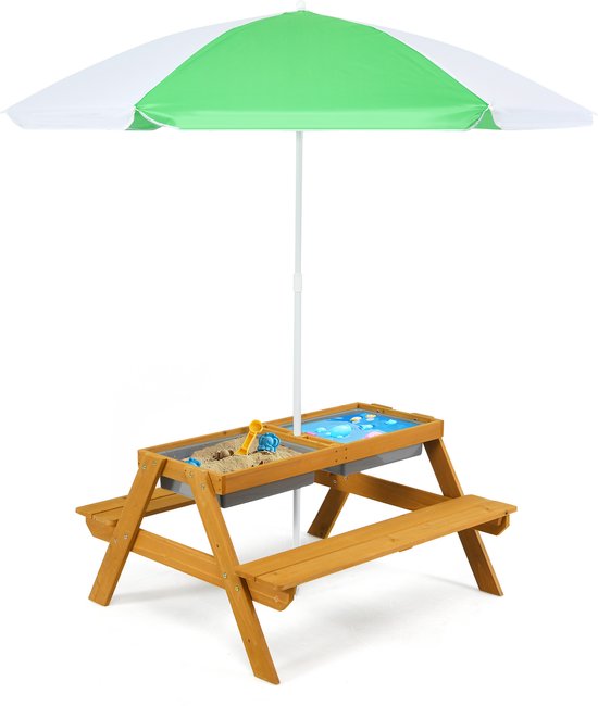 Een houten kinderpicknicktafel met groen-witte parasol, zand- en waterbakken, geïsoleerd op een witte achtergrond.