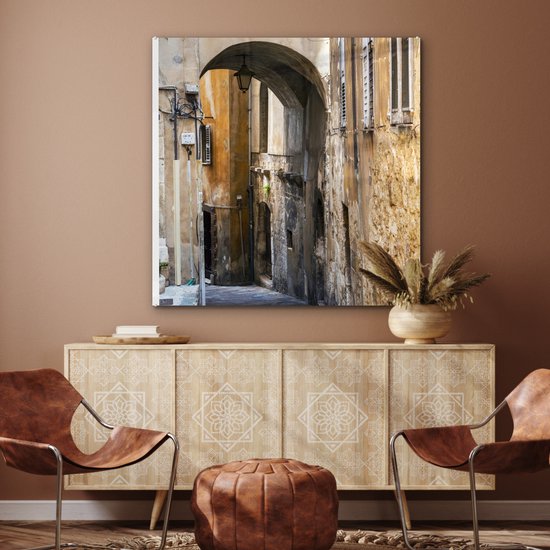 ® Glasschilderij 90x90 cm - Schilderij acrylglas - Stenen boog in een steegje tijdens een zonnige dag - Foto op glas - Muurdecoratie woonkamer - Wanddecoratie slaapkamer - Schilderijen