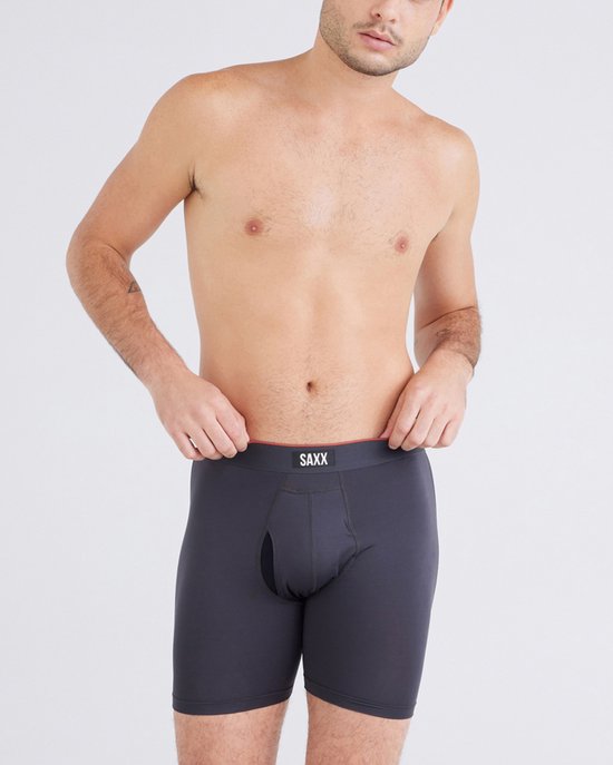 Man in donkergrijze SAXX boxershort met rode bies.