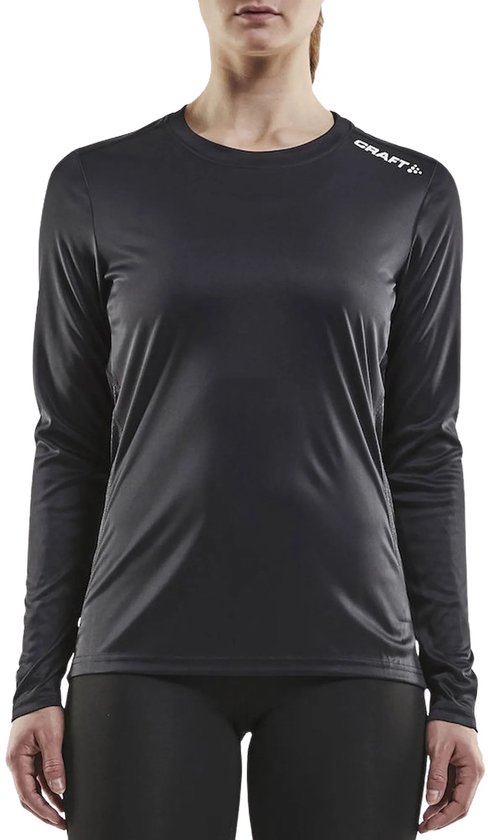 Vrouw in een zwart Craft sportshirt met lange mouwen en zwarte sportlegging.