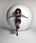 Model met krullend haar in een zwarte strapless beugel-bh en zwarte panty.