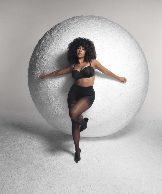 Model met krullend haar in een zwarte strapless beugel-bh en zwarte panty.