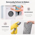 Grijze antislip douchemat wordt in de wasmachine gewassen en met de hand afgespoeld onder een douchekop.
