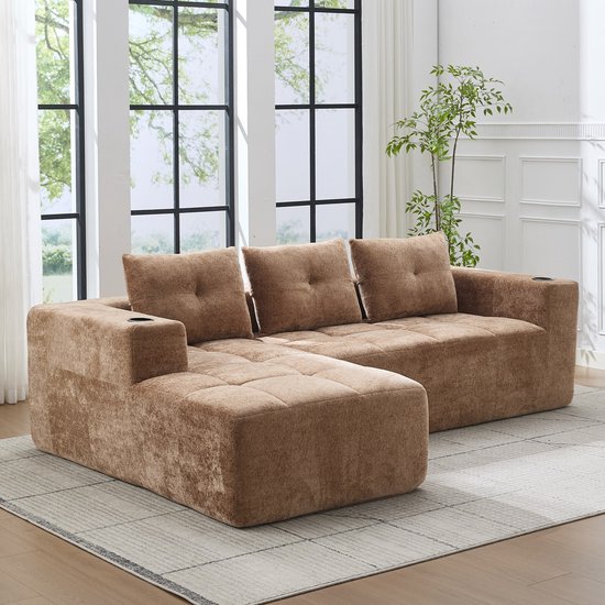 Lichtbruine chenille L-vormige bank met een chaise longue, zitkussens en bekerhouders, bij een raam.