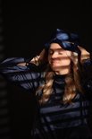 Een vrouw met blond haar met gesloten ogen draagt een donkerblauw zijden slaapmasker van Slowwave.