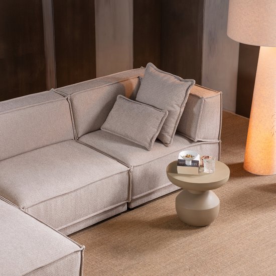 Dichtbij van een beige modulaire bank met twee kussens en een bijzettafel.