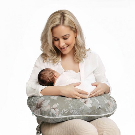Vrouw met blonde haren voedt baby op grijs voedingskussen met bloemenprint.