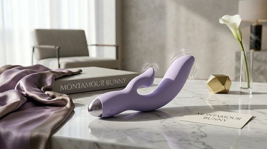 Paarse vibrator met zilveren punt op een marmeren tafel, naast een boek en een gouden decoratie.