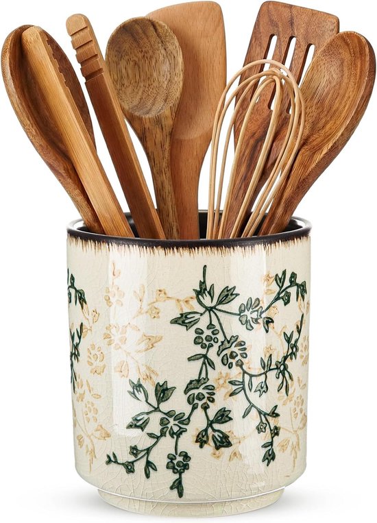 Crème keramische houder met groene en gele bloemenprint, gevuld met houten keukengerei.