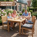 Familie zit aan tafel in de tuin, met donkergrijze vierkante kussens op de stoelen. Voor gezellige dagen buiten.