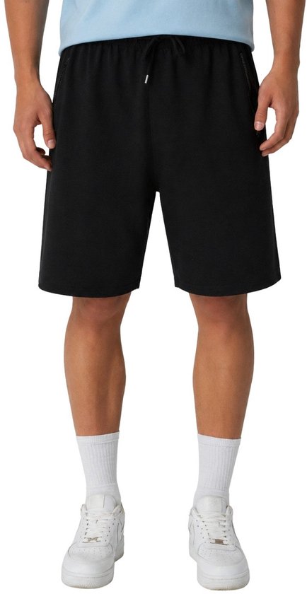 Man met zwarte short met trekkoord, witte sokken en witte sneakers.