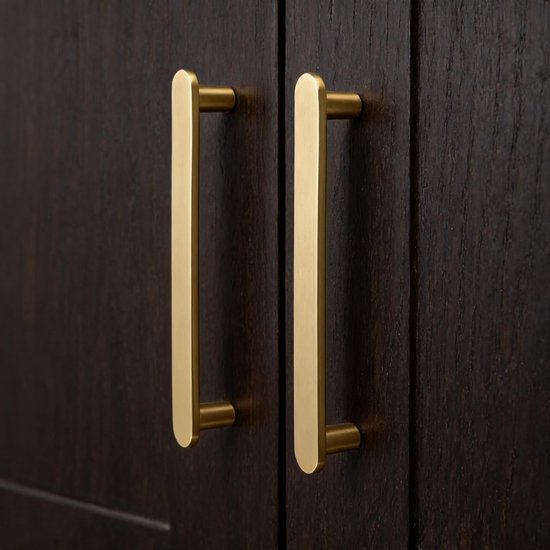 Twee matte messing handgrepen met gouden kleur op donkerbruine kasten.