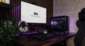 Gaming pc setup met paarse accentverlichting. De pc is voorzien van een groot scherm, toetsenbord, muis en gaming koptelefoon.