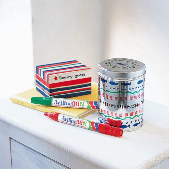 Artline 90N markers, rood en groen, op een witte kast naast een blik met vismotief.
