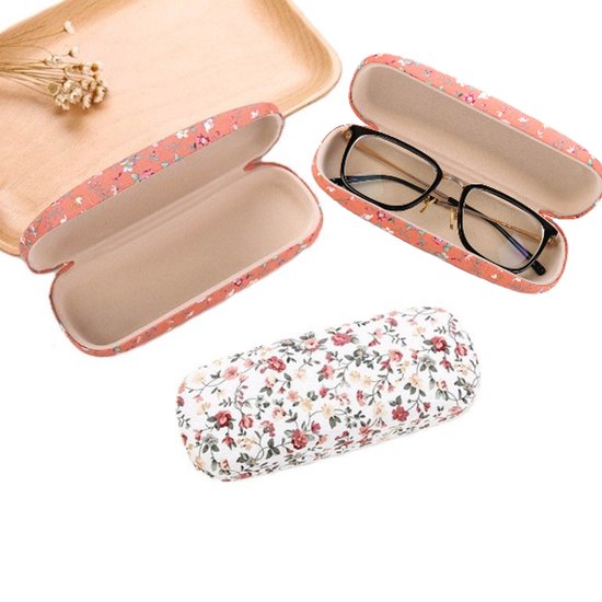 Open roze brillenkoker met bloemenprint, een gesloten witte brillenkoker en een open roze brillenkoker met bril.