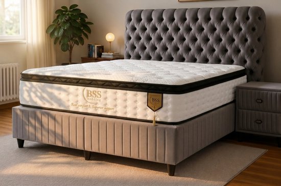 Een gestoffeerd grijs hoofdbord met een matras met zwarte en gouden randen, met "BSS Bedding" logo.