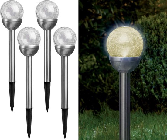 Vier tuinlampen met zilverkleurige paal en een glazen bolkap. Eén lamp is in gebruik en geeft wit licht in een tuin.