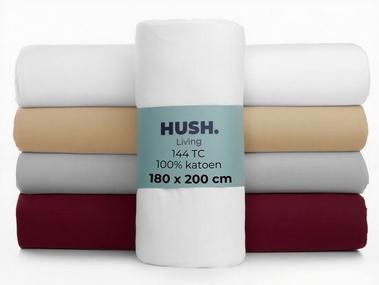 Stapel van vier hoeslakens in wit, beige, grijs en bordeauxrood. De witte hoeslaken in het midden toont het HUSH. Living label met '144 TC, 100% katoen, 180x200 cm'.
