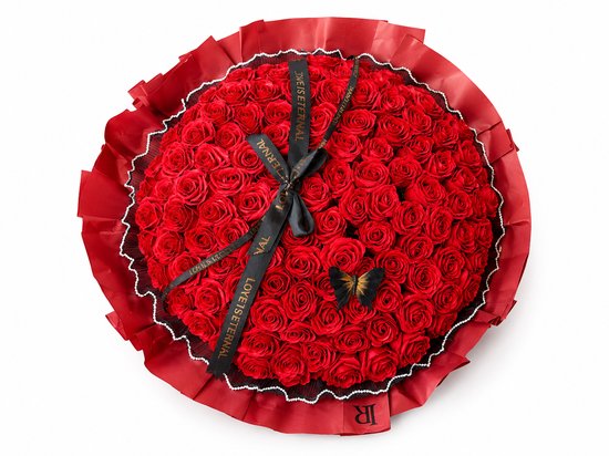 Vue de dessus d'un bouquet de roses rouges, bordé de perles et orné d'un papillon noir. Rubans noirs "LOVE IS ETERNAL".