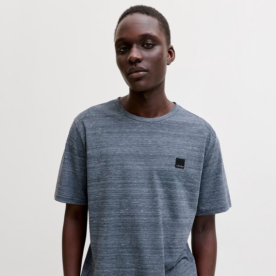 Donkerblauwe, gemêleerde T-shirt met korte mouwen met een zwart logo-label op de borst, gedragen door een man.