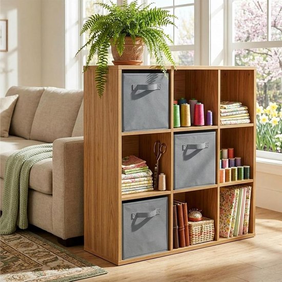Houten kast met stoffen opbergbakken in grijs, gevuld met knutselspullen en planten.