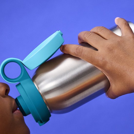 Kind drinkt uit zilverkleurige drinkfles met turquoise dop.