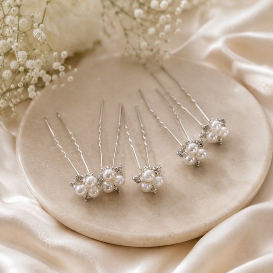 Six épingles à cheveux argentées avec un motif floral de perles et de strass sur une assiette incurvée.