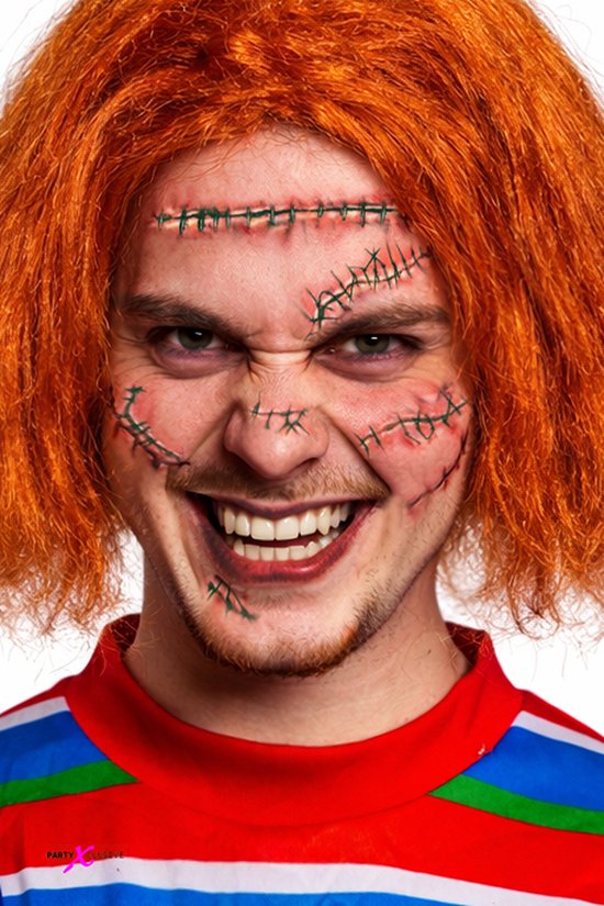 Close-up portret van een persoon met oranje pruik en neplittekens op het gezicht, met een grimmige grijns.