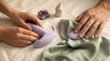 Handen nemen een paarse vibrator en afstandsbediening van een wit tafellaken met decoratieve elementen.