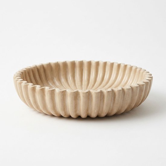 Beige aardewerk schaal met verticale ribbels aan de buitenzijde en golvende rand.