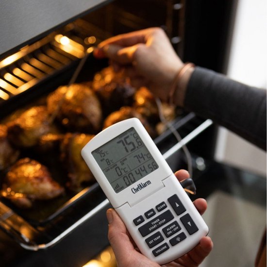 ChefAlarm oventhermometer met digitaal display, naast een pan met geroosterde kip in een oven.