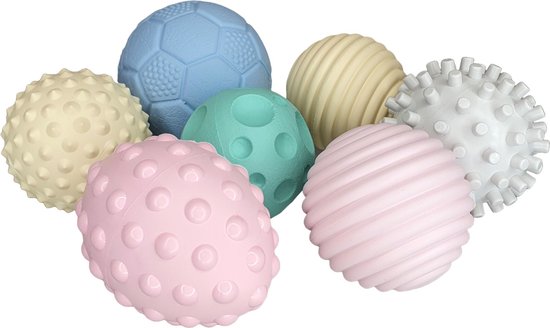 Zeven zachte, getextureerde ballen in pastelkleuren, waaronder een blauwe voetbal, een mintgroene bal met ronde inkepingen, een roze bal met noppen, een gele bal met ribbels, en een grijze bal met stekeltjes.