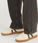 Crèmekleurige Jack & Jones sneakers met zwarte strepen, gedragen met een donkere jeans.
