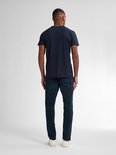Man met donkerblauwe jeans met rechte pasvorm en donkerblauw t-shirt, van achteren gezien.