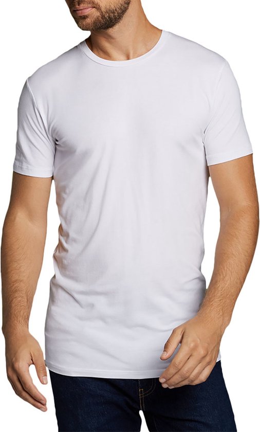 Man met baard draagt een wit T-shirt en een spijkerbroek.