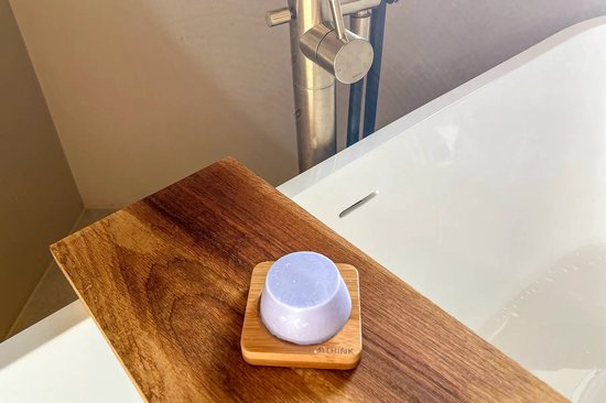 Paarse RTHINK conditioner bar op een houten dienblad in een badkuip.
