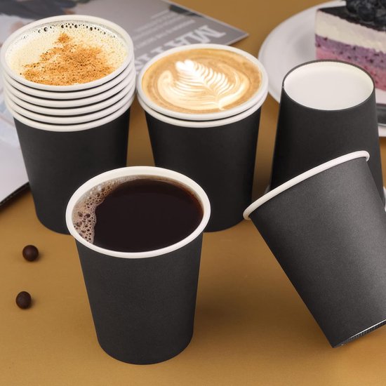 Zwarte koffiebekers gevuld met koffie, cappuccino en latte macchiato. Zichtbaar zijn ook wat koffiebonen.