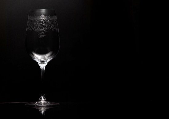 Élégant verre à champagne avec des gravures complexes, éclairé sur fond noir.