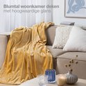 Gele plaid op een bank in een woonkamer.